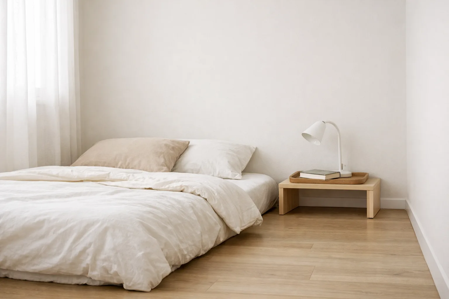 Un lit bas avec une petite table de chevet à hauteur du matelas et un passage dégagé le long du mur.