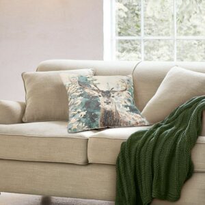 Housse de coussin Elvaris avec cerf, sapins enneigés et détails brodés