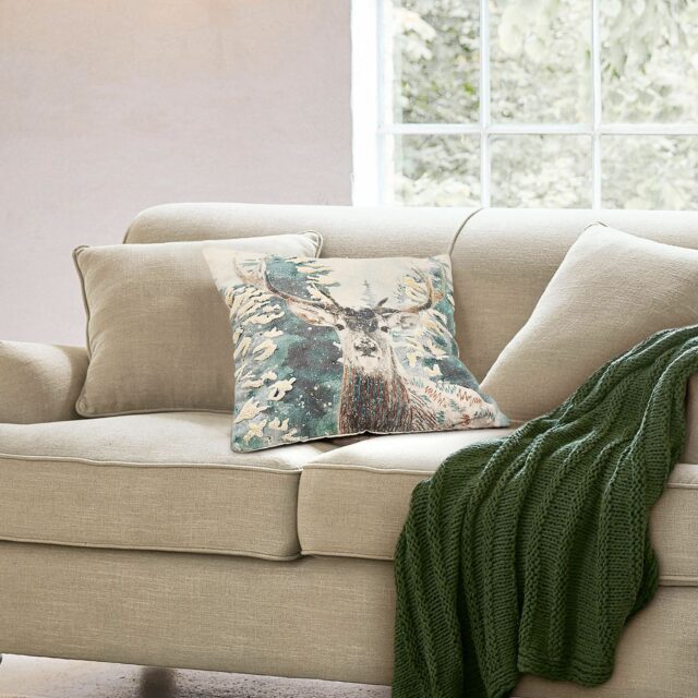 Housse de coussin Elvaris avec cerf, sapins enneigés et détails brodés